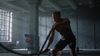 Spor salonunda halatlarla antrenman yapan bir adam. Sporcu yoğun fitness egzersizi yapıyor