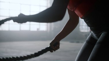 Savaş halatlarıyla çalışan bir sporcu. Crossfit egzersizi yapan kadın.