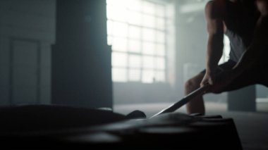 Lastiğe çekiçle vuran bir adam. Balyozla egzersiz yapan adam.