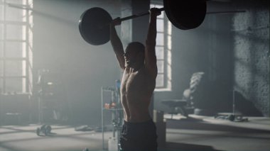 Adam halterle tepetaklak oturuyor. Güçlü sporcu ağırlık kaldırıyor. 