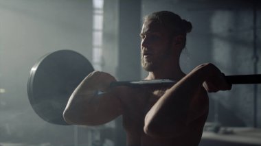 Güç toplayıcı antrenman sırasında ağırlık kaldırıyor. Ön koltukta halterle oturan adam.