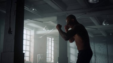 Kickboksör, spor kulübünde gölgelerle dövüşüyor. Sporcu dövüşmeye hazırlanıyor.