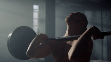 Adam antrenman sırasında halterle çömelmiş. Spor salonunda spor yapan erkek vücut geliştirici.