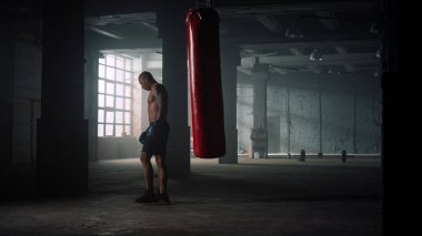 Boksör antrenman sırasında kum torbası tekmeliyor. Adam spor çantasında tekme antrenmanı yapıyor.