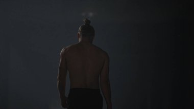 Çatı katında yürüyen atletik bir adam. Adam antrenman arasında mola veriyor. 