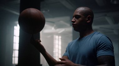 Odaklanmış adam parmak üzerinde dönen top. Sporcu basketbol topuyla oyun oynuyor.