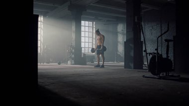 Spor malzemeleriyle spor salonunda duran adam. Bir adam halteri yerden alıyor.