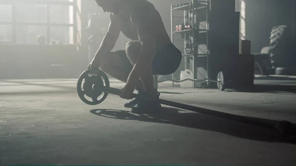 Мужчина ходит в кроссфитовом спортзале. Культурист готовит спортивный инвентарь для тренировок — стоковое фото