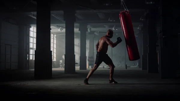 Мужчина боксер бьет спортивную сумку. Злобный человек отрабатывает удары по боксерской груше — стоковое фото