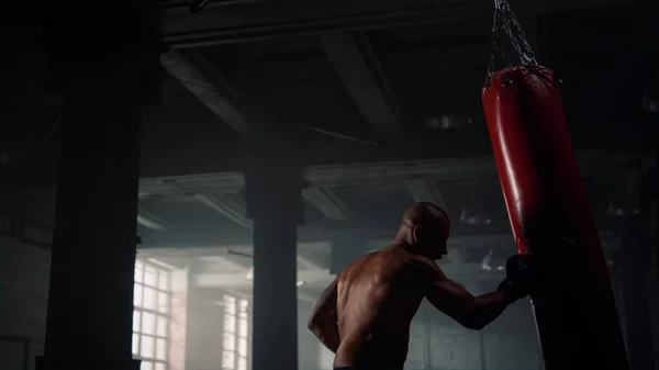 Boxeador masculino saco de boxeo en el club deportivo. Hombre enojado pateando saco de boxeo — Foto de Stock