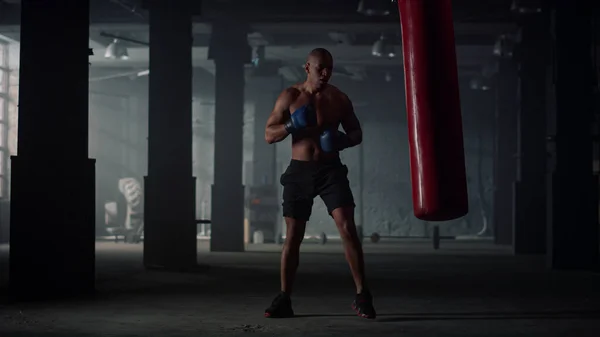 Muž bít boxovací pytel během intenzivního cvičení. Mužský boxer cvičí kickbox — Stock fotografie