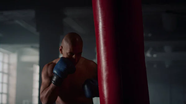 Boxeo masculino saco de boxeo en el gimnasio. Sportsman sin camisa kickboxing bolsa de deporte — Foto de Stock
