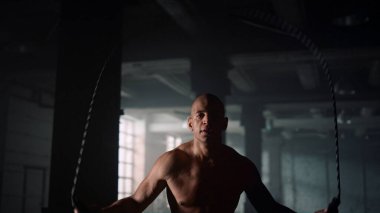 Spor salonunda ip atlayan bir adam. Sporcu kardiyo egzersizi yapıyor