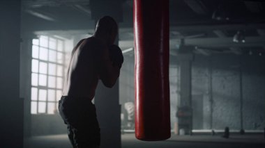 Eldivenle kum torbasına vuran bir sporcu. Spor çantasına sakso çeken adam.