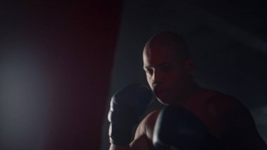 Boksör spor salonunda kum torbasına tekme pratiği yapıyor. Kızgın adam boks çantası.