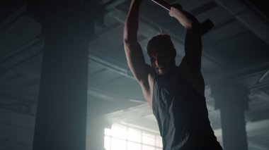 Adam güç egzersizi için çekiç kullanıyor. Lastiğe vuran jimnastikçi. 