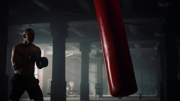 Man boxare gör intensiv träning i sport klubb. Afro man sparkar slagsäck — Stockfoto