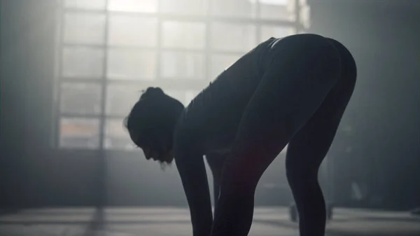 Sportkvinnan böjer sig framåt under träningen. Kvinnlig kroppsbyggare uppvärmning kropp — Stockfoto