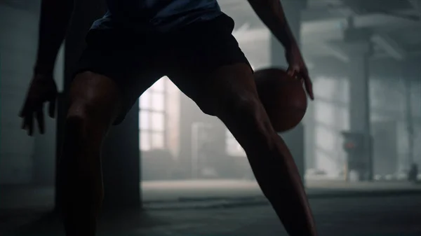 Basketballspieler beim Spiel. Mann springt Basketballball zwischen die Beine — Stockfoto