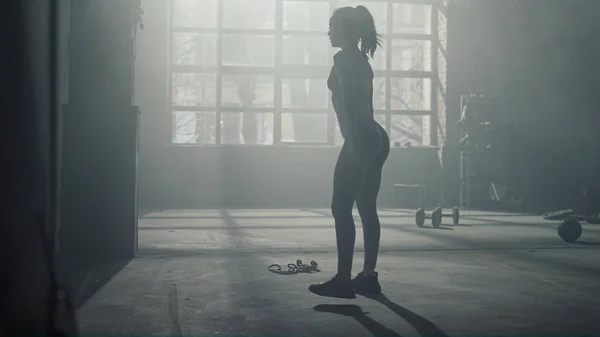 Nainen tekee kyykkyjä treenatessaan kuntosalilla. Tyttö tekee jalka harjoitus — kuvapankkivalokuva