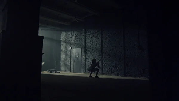 Спортивная спортсменка бросает мяч на бетонную стену в здании лофта — стоковое фото