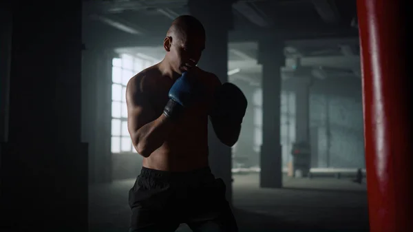 Boxer exersând lovituri pe sac de perforare în sala de sport. Guy box sport sac în mănuși Fotografie de stoc