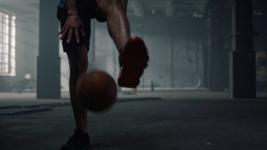 Bacaklarının arasında basketbol topu sektiren bir adam. Basketbol oynayan erkek oyuncu 