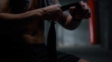 Spor salonunda boks kasetleriyle el ele tutuşan bir boksör. Kum torbası kullanan afro adam.