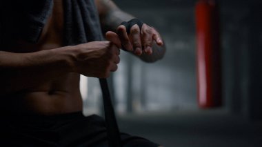 Boksör spor salonunda boks sargılarını kullanıyor. Elleri boks kasetleriyle saran adam.