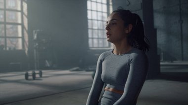 Spor salonunda beden eğitimi dersinde yerde oturan bir kadın. Sporcu ağır nefes alıyor