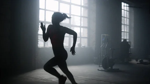 ダークロフトビルでアクティブなスポーツウーマンジョギング。ジムで走る強い女性 — ストック写真