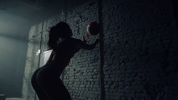 女は体重の重いボールでスクワットをする。女の子投げフィットボールに対して壁 — ストック写真