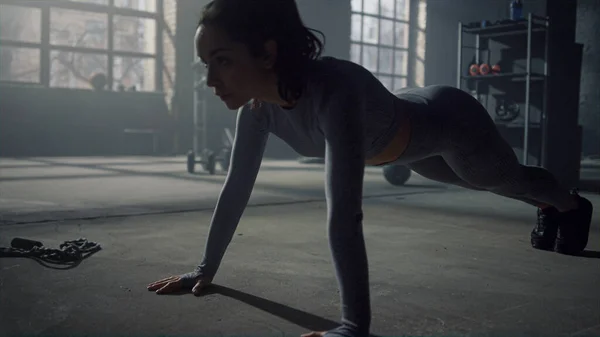 Atleta haciendo flexiones en el gimnasio. Mujer haciendo entrenamiento de fitness en el edificio loft — Foto de Stock
