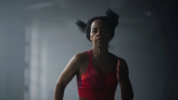 Спортивна дівчина біжить у спортзалі. Жінка біжить швидко в темному коридорі будівлі горища — стокове фото