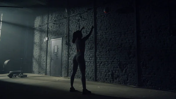 Kobieta robi przysiady z piłką pod ścianą. Kulturysta robi trening crossfit — Zdjęcie stockowe