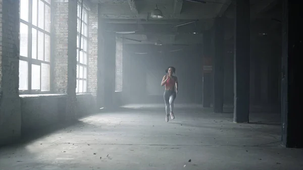 Entrenamiento de deportista en loft building. Corredor femenino corriendo en gimnasio — Foto de Stock