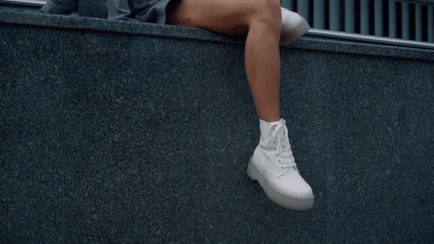 女性モデルの足はダウンタウンの都市建築都市でポーズ座っている. — ストック動画