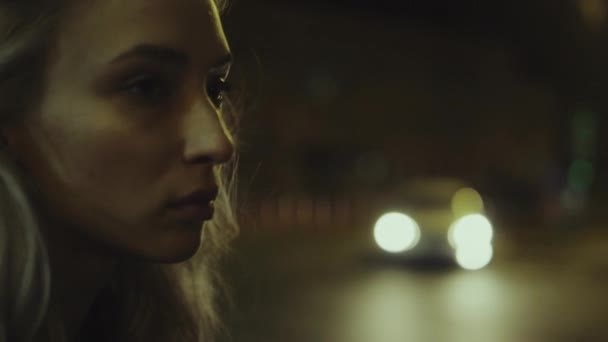ブロンド女性の街の夜の顔通りのライトを通過車を見て. — ストック動画