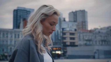 Sakin bir kadın, şehir meydanında, şehir binalarının yanında duruyor.. 