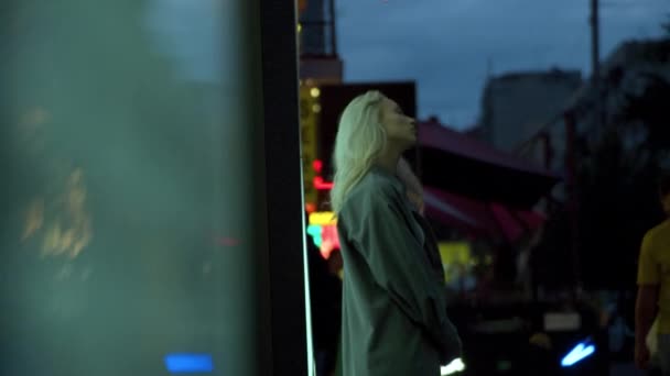 Blond meisje wachten stad dragen casual kleding in de avond stedelijk gebied. — Stockvideo