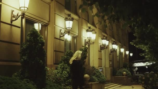 Mujer caminando calle sola por la noche en las luces modernas de la ciudad. — Vídeo de stock