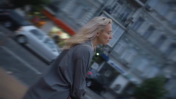 Nyugodt nő megy ki a városba sétálni az esti városi úton elhaladó autókkal. — Stock videók