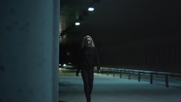Mujer de ciudad nocturna caminando con confianza con cabello rubio en túnel subterráneo. — Vídeo de stock