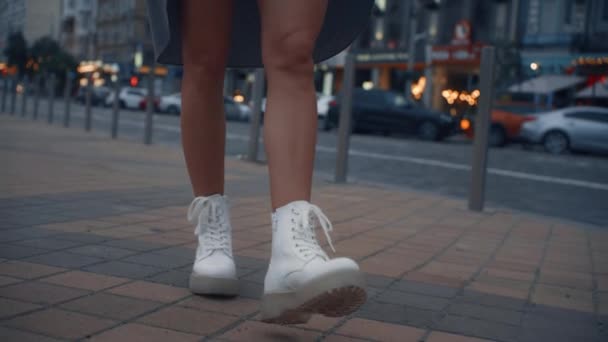 Weibliche Beine laufen Straße in Abendstadt in der Nähe von Autobahnampeln hinunter. — Stockvideo