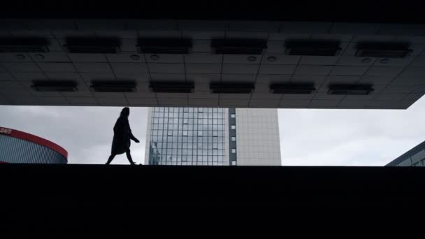 Silueta persona femenina caminando en edificio oscuro en el centro de la ciudad. — Vídeo de stock