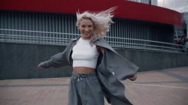 Şehir merkezinde şehir binalarının yakınında yürüyüşe çıkan mutlu kadın..