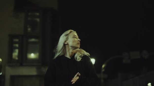 Vonzó lány séta város egyedül kapucnis pulcsiban az éjszakai fények utcán. — Stock videók