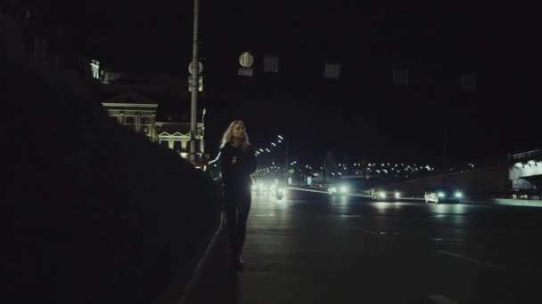 Kobieta spacerując po mieście noc na autostradzie sam w miejskiej ulicy. — Wideo stockowe
