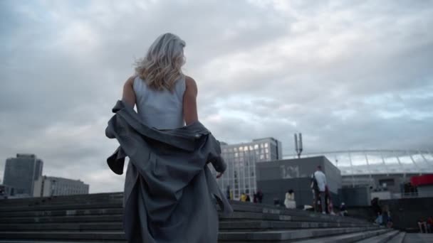 Frau beim Treppensteigen im urbanen Hintergrund in verregneten modernen Gebäuden. — Stockvideo