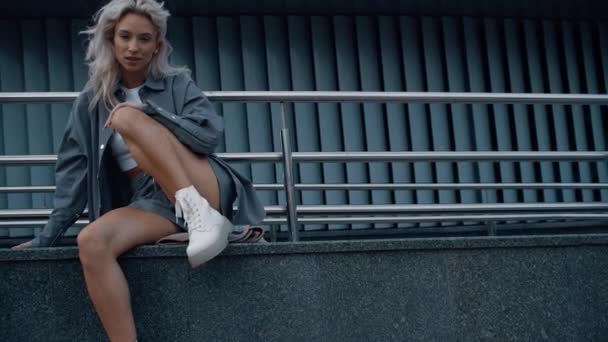 Mujer de moda modelando fondo urbano sentado en el edificio. — Vídeos de Stock